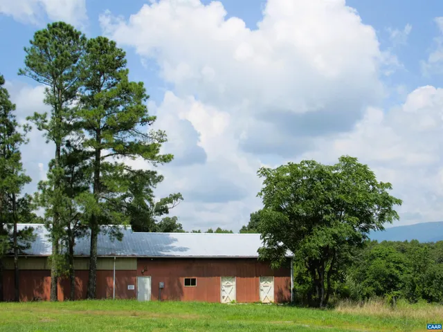 a view of a house with a big yard and large trees