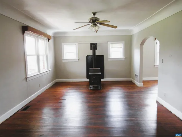 a view of room with wooden floor a ceiling fan and windows