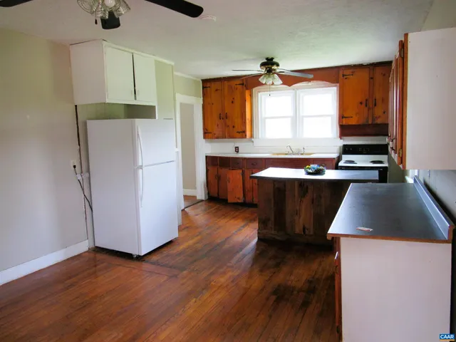 a kitchen with wooden floors and white stainless steel appliances