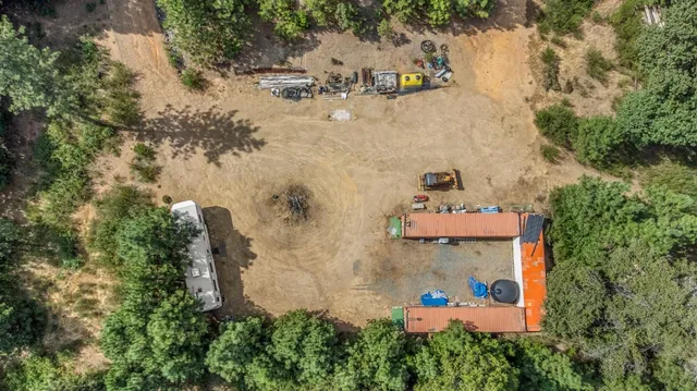 an aerial view of a house with a yard and large trees