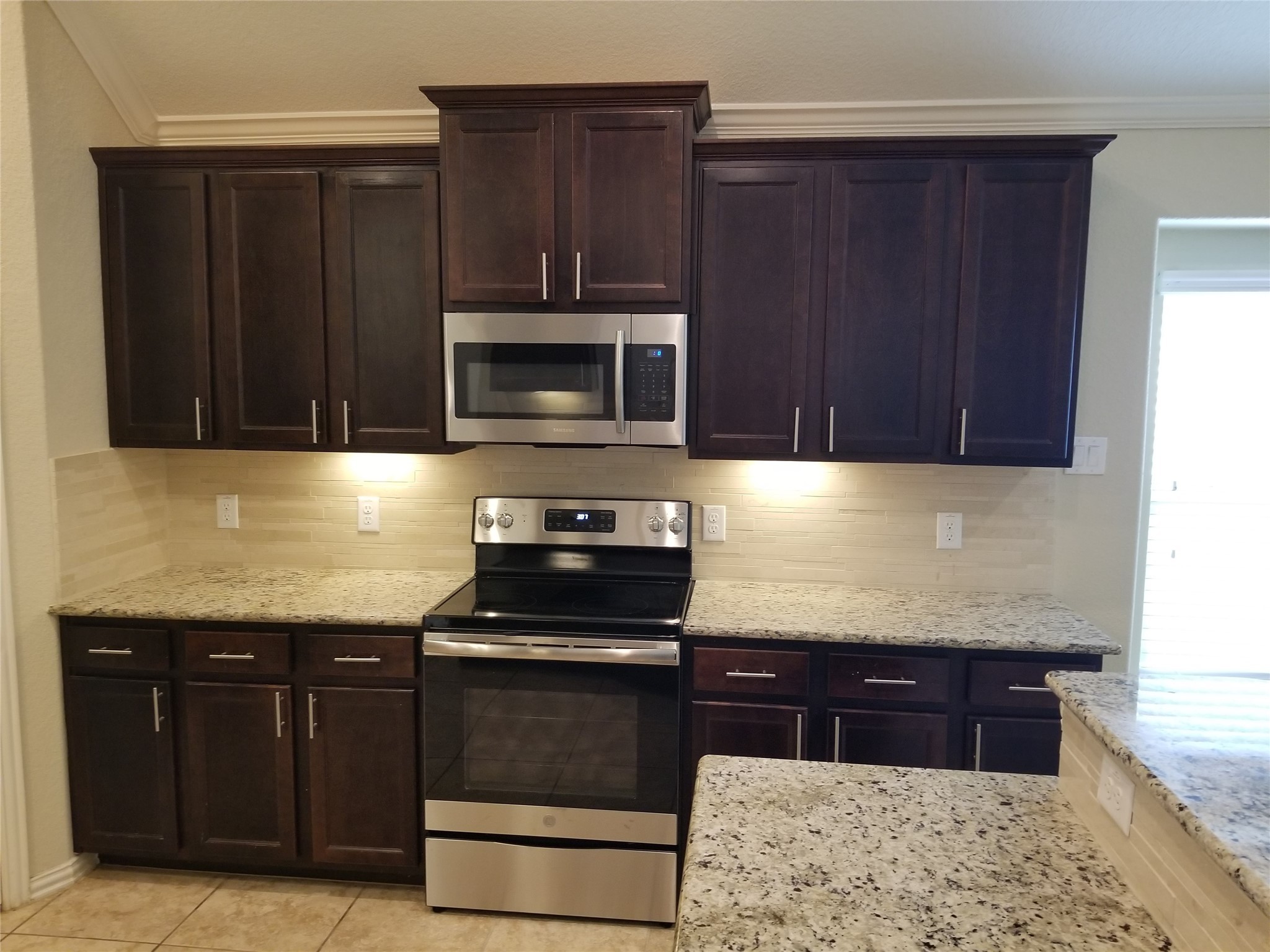 5217 Green Heath Lane Rosharon, TX 77583 - Photo 3 of 18 a kitchen with granite countertop stainless steel appliances a stove a microwave and cabinets