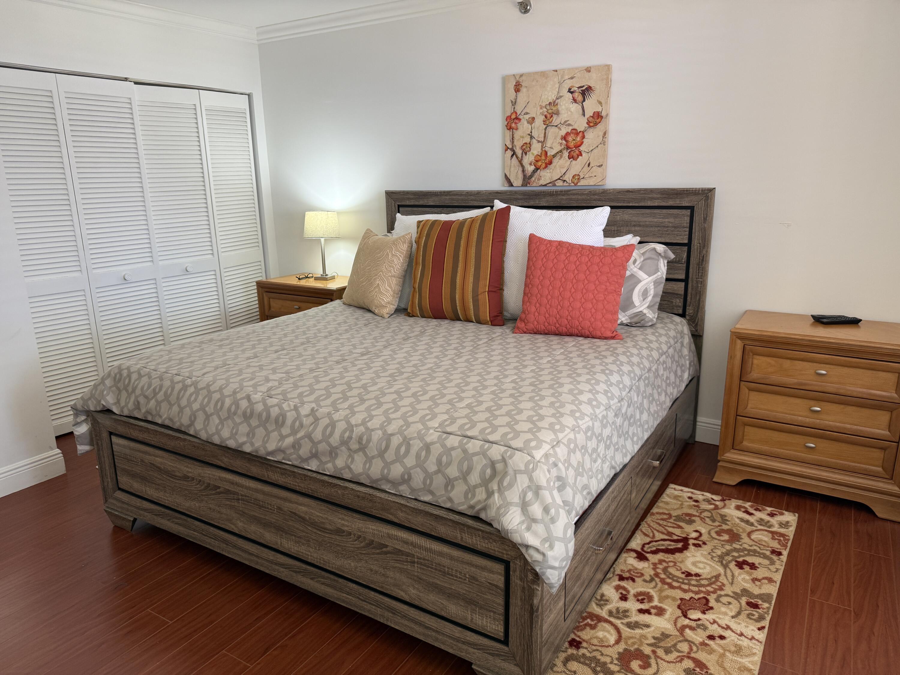 7194 Promenade Drive, Unit 102 Boca Raton, FL 33433 - Photo 22 of 56 a bedroom with a bed and a lamp on dresser