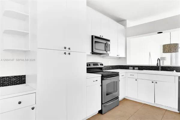 a kitchen with granite countertop white cabinets and stainless steel appliances