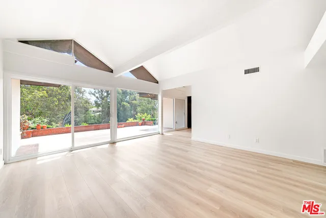 a view of an empty room with wooden floor and windows