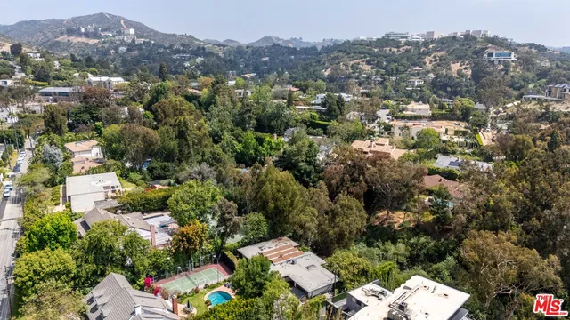an aerial view of a houses with a lush green hillside