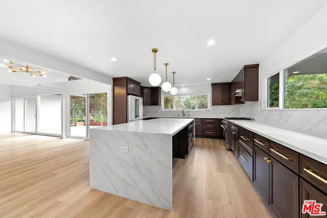 a large kitchen with stainless steel appliances granite countertop a large counter top a sink dishwasher and a stove with wooden floor