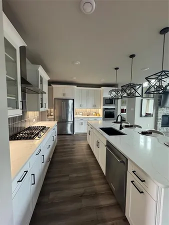 a large kitchen with stainless steel appliances granite countertop a lot of counter space and wooden floor