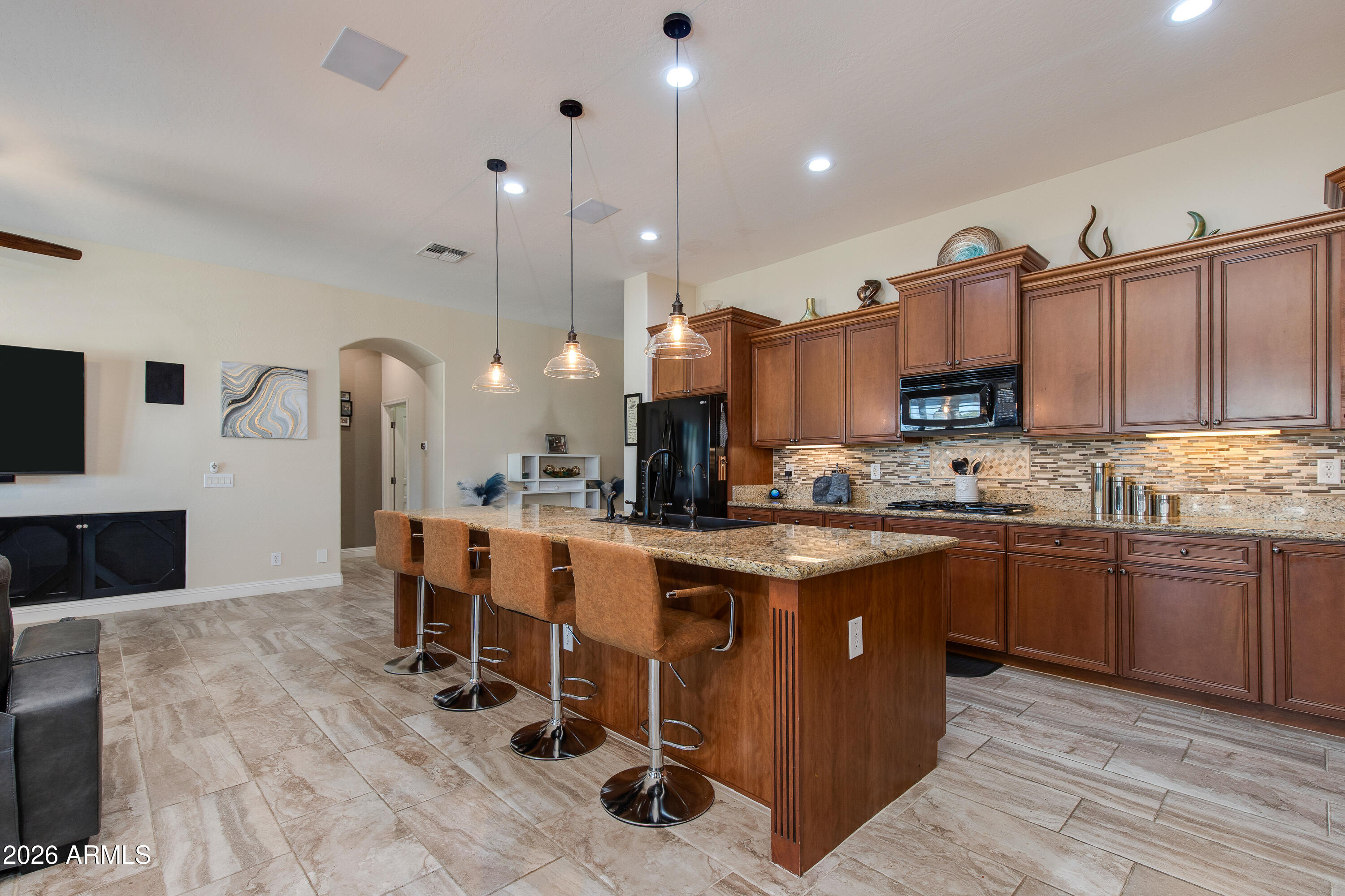 7718 North 84th Lane Glendale, AZ 85305 - Photo 11 of 82 a kitchen with stainless steel appliances kitchen island granite countertop a table chairs sink and cabinets