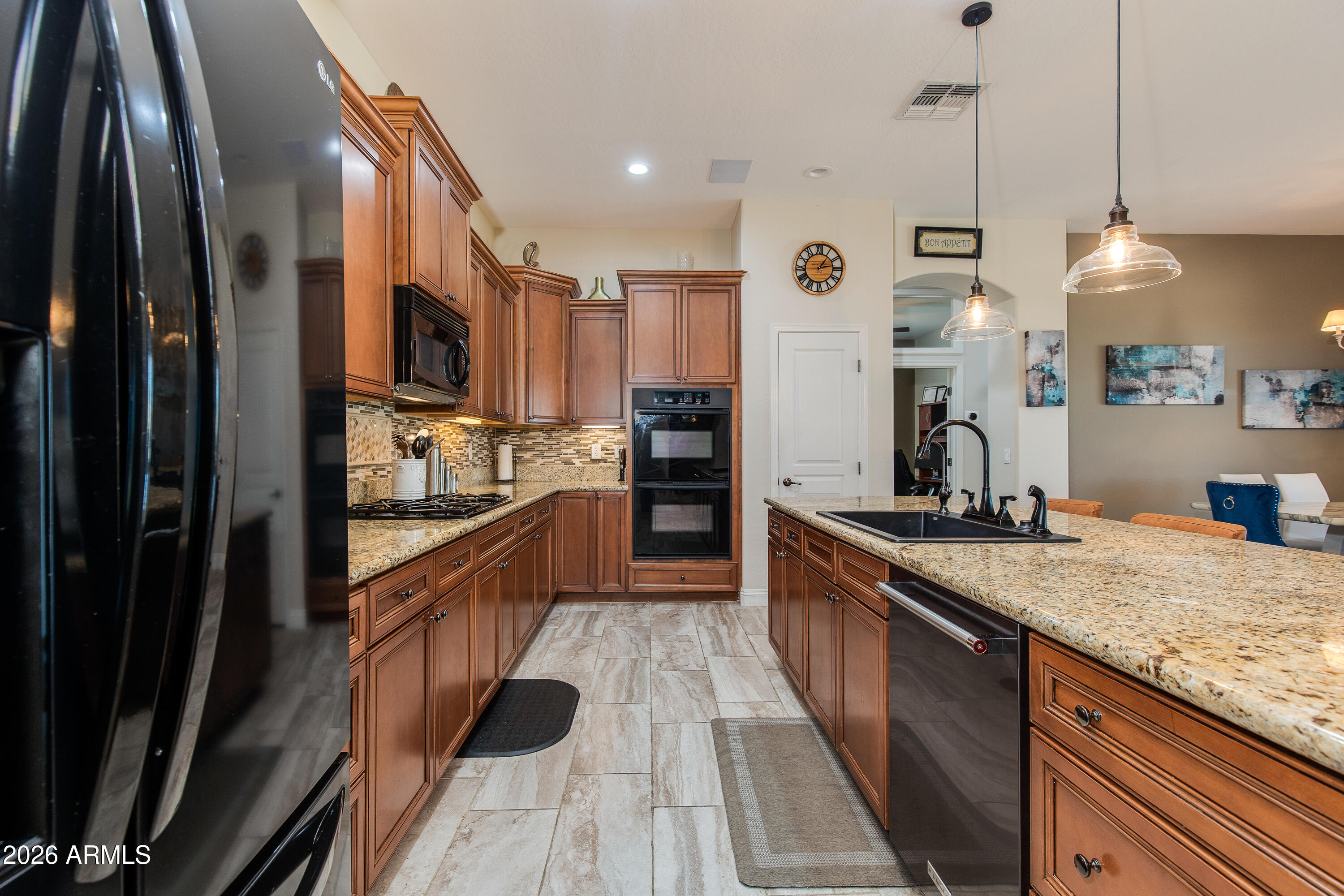 7718 North 84th Lane Glendale, AZ 85305 - Photo 16 of 82 a large kitchen with stainless steel appliances kitchen island granite countertop a refrigerator a stove and a sink