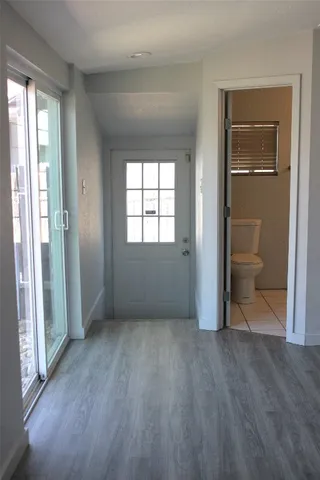 an empty room with wooden floor cabinet and windows