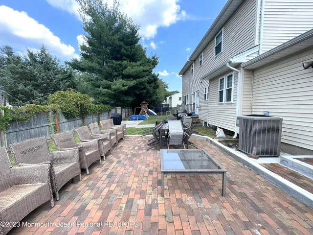 a view of a patio with couches and table and chairs with wooden floor and fence