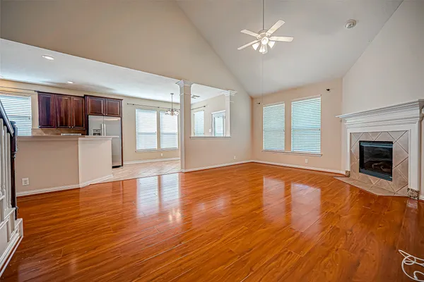 a view of an empty room with a kitchen and wooden floor