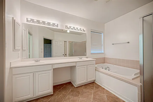 a bathroom with a bathtub a double vanity sink and mirror