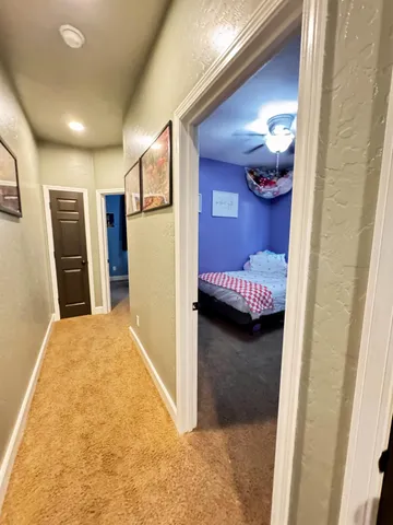 a view of a livingroom with a fireplace a chandelier fan and wooden floor