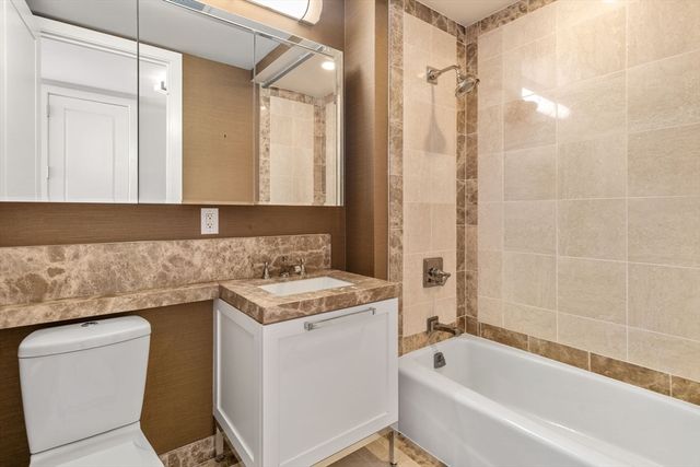 a bathroom with a granite countertop sink a toilet and shower