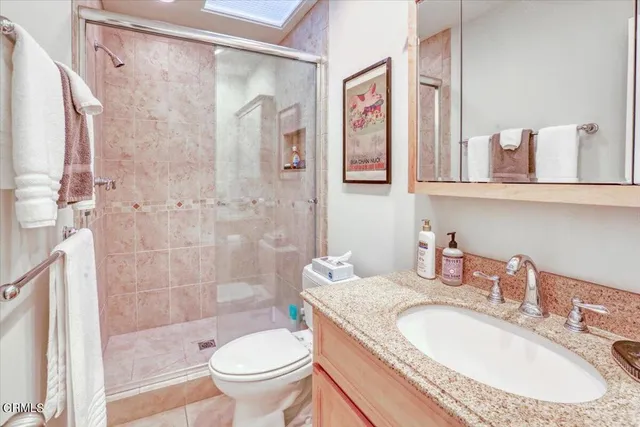 a bathroom with a granite countertop sink a toilet and shower