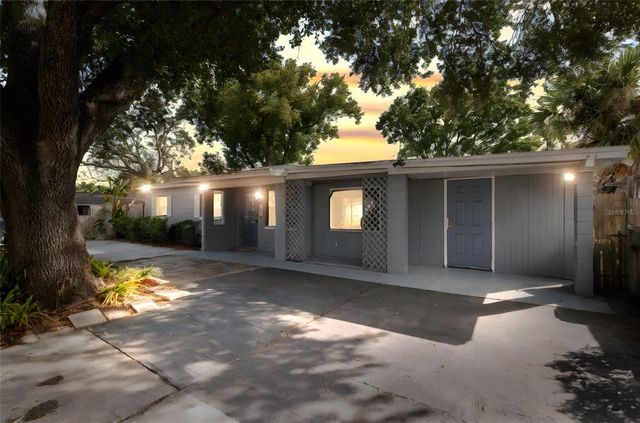 a view of a house with a yard and large tree