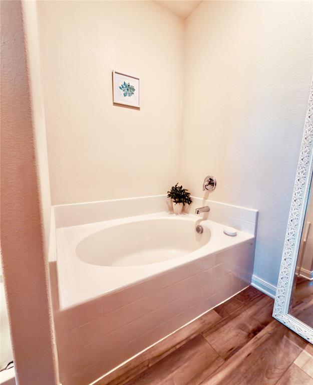 196 Cattlemans Crk Road West Newark, TX 76071 - Photo 9 of 24 Built-in soaking tub with chrome fixtures, surrounded by light-toned wall paint and wood-finish flooring
