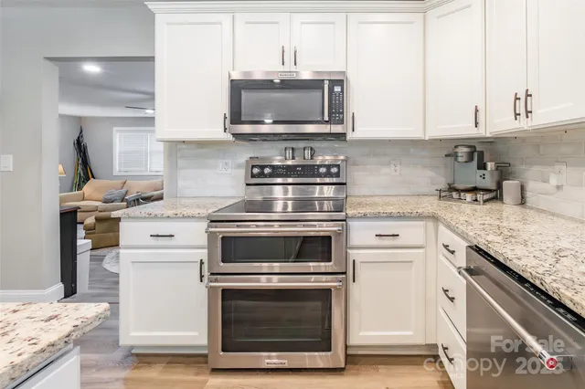 a kitchen with stainless steel appliances granite countertop a stove microwave and cabinets
