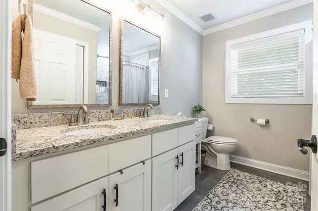 a bathroom with a granite countertop sink toilet and mirror