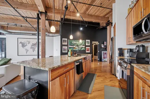 a kitchen with stainless steel appliances granite countertop a sink a stove and a wooden cabinets
