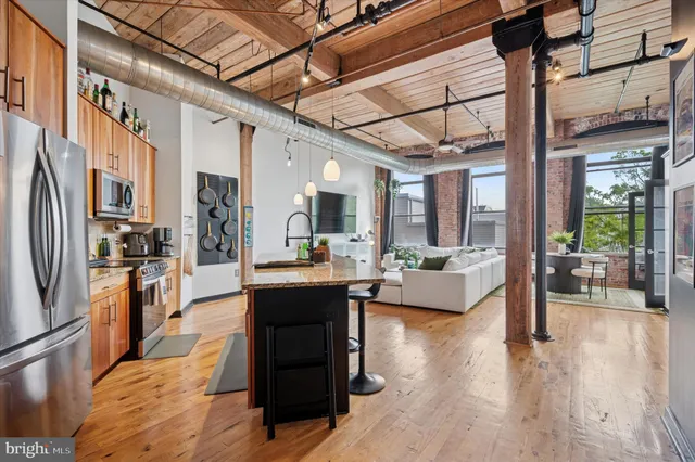 a living room with stainless steel appliances furniture wooden floor and a chandelier