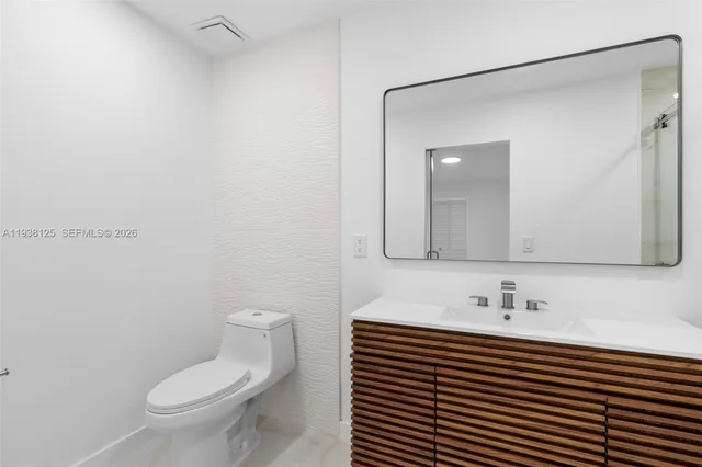 a bathroom with a sink a toilet a mirror and shower