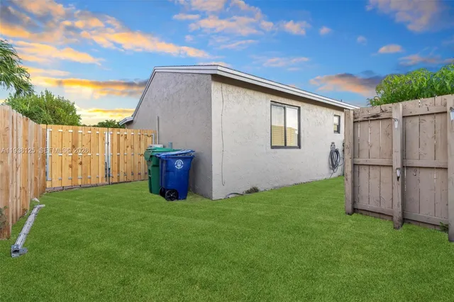 a view of a backyard with wooden fence and a bench