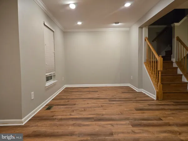 a view of an empty room with wooden floor and stairs