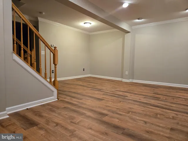 a view of an empty room with wooden floor and windows