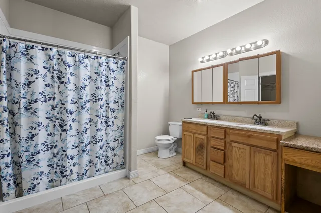 an empty room with chandelier fan and windows