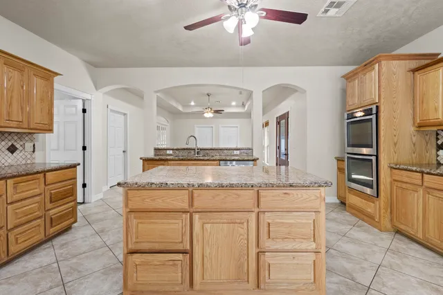 a kitchen with granite countertop a stove top oven and cabinets