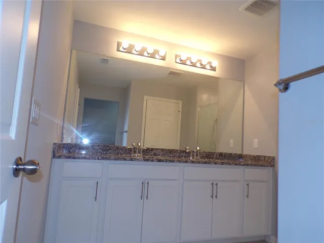 a bathroom with a granite countertop sink and a mirror