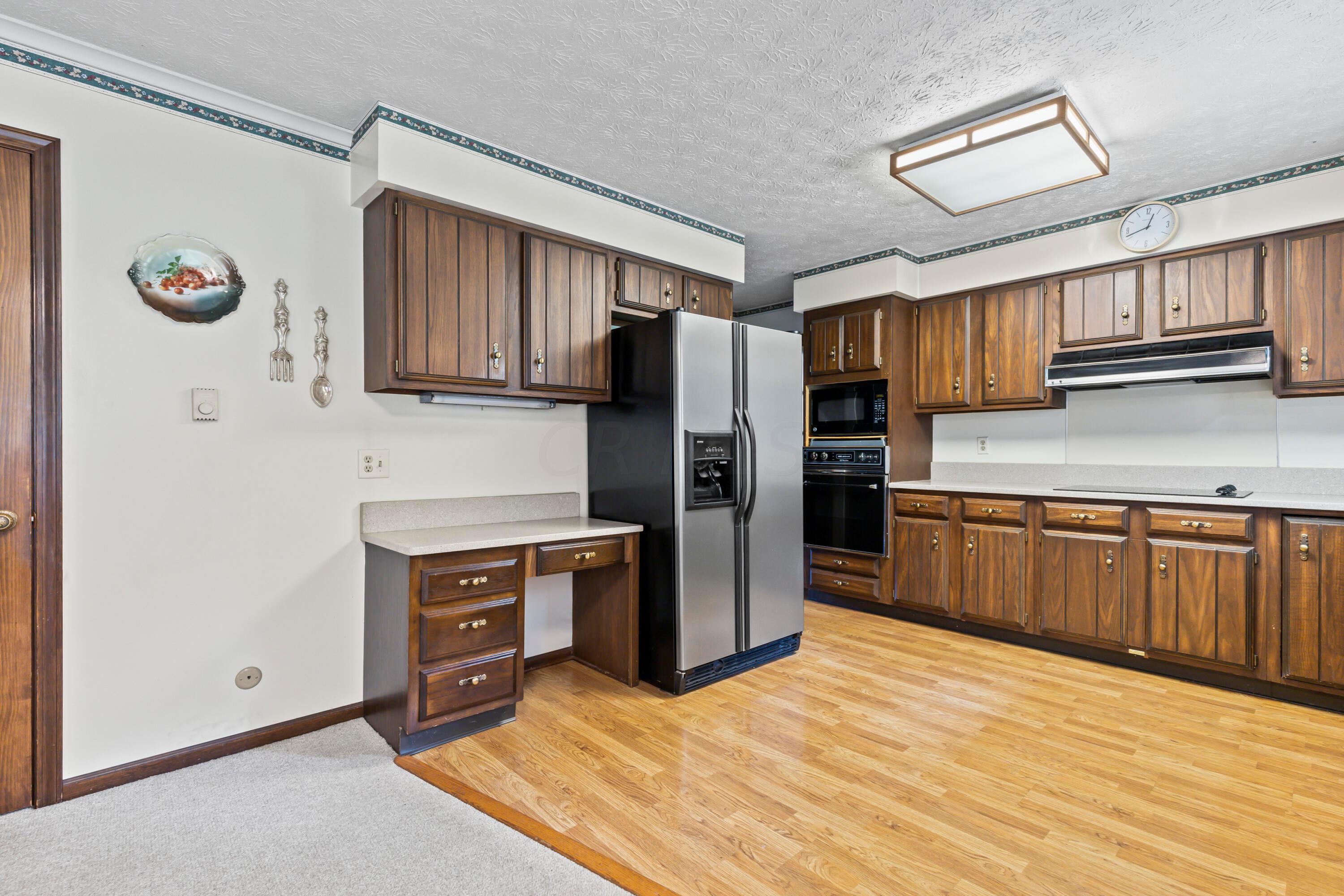 5764 Cheshire Road Galena, OH 43021 - Photo 28 of 59 • Laminate flooring
• Ivory painted walls
• Ceiling light
• Fluted wood cabinets
• Updated granite countertops
• JennAir® dishwasher
• Disposal
• Range hood
• Lazy Susan
• General Electric® electric
range top
• Kenmore® refrigerator
• Planning desk
• JennAir® oven
• General Electric® microwave
