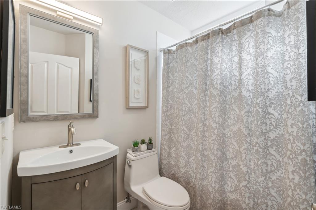 1747 Reuven Circle, Unit 1703 Naples, FL 34112 - Photo 14 of 31 a bathroom with a toilet a sink and a mirror