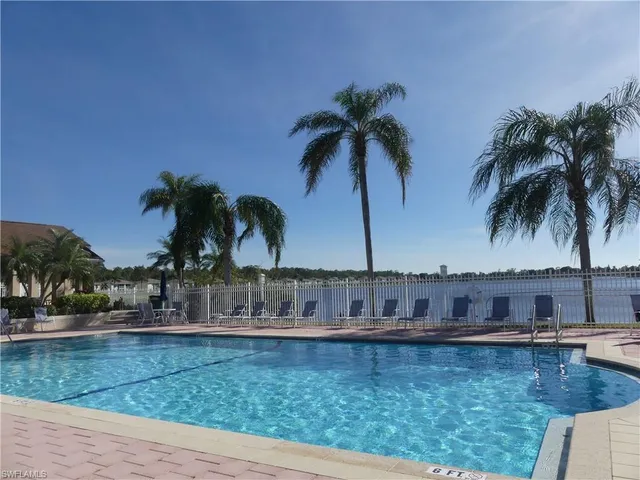 a view of swimming pool with a yard and palm trees