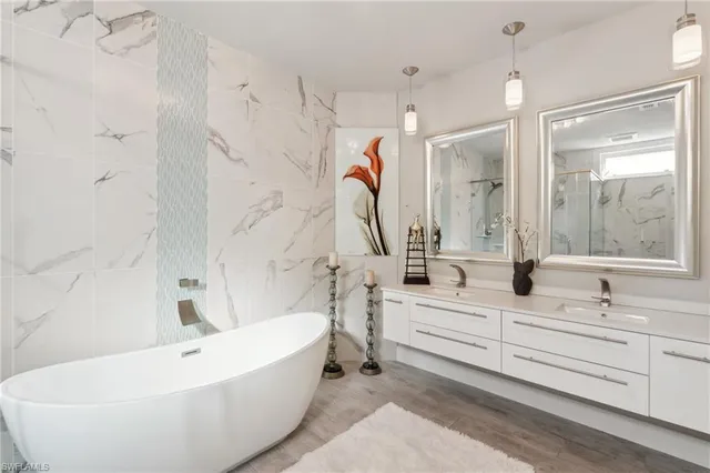 a bathroom with a double vanity sink mirror and bathtub