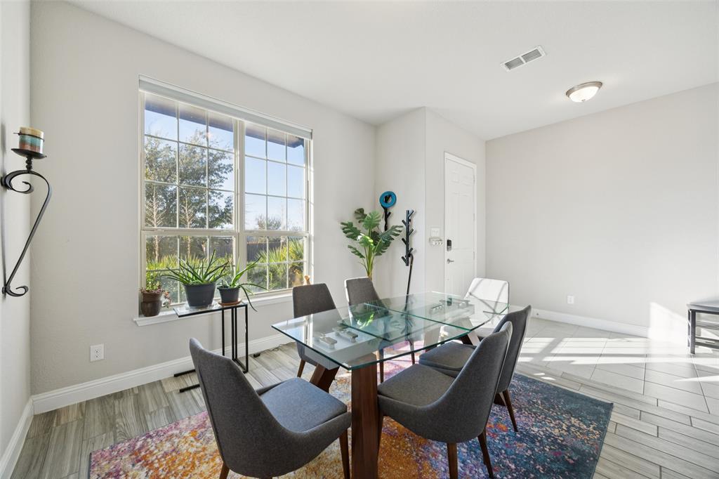 1701 Long Meadow Road Wylie, TX 75098 - Photo 10 of 30 a dining room with furniture potted plants and wooden floor