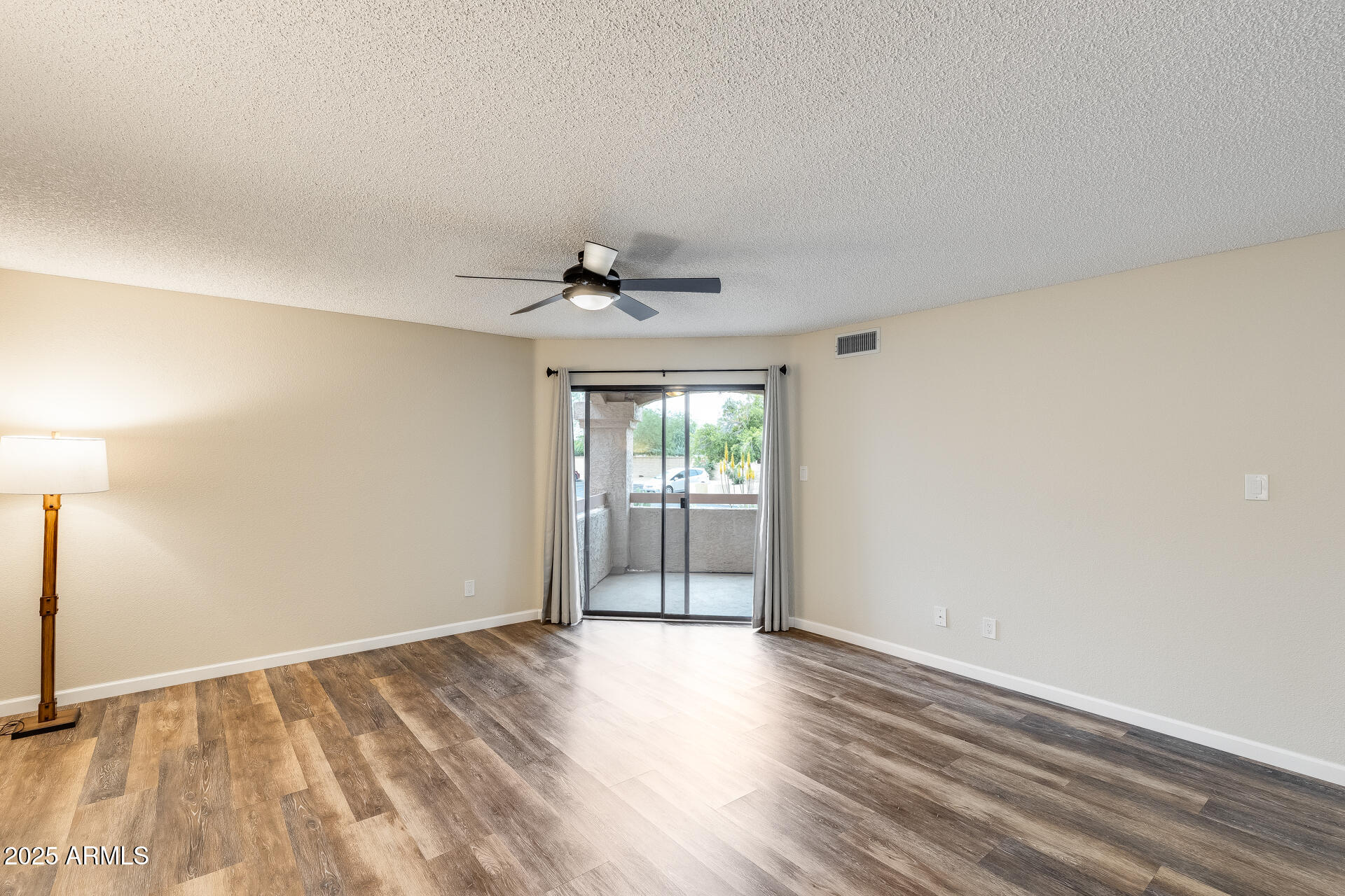 9151 West Greenway Road, Unit 111 Peoria, AZ 85381 - Photo 12 of 45 a view of an empty room with wooden floor and a window