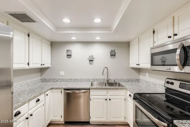 a kitchen with granite countertop a sink stainless steel appliances and white cabinets