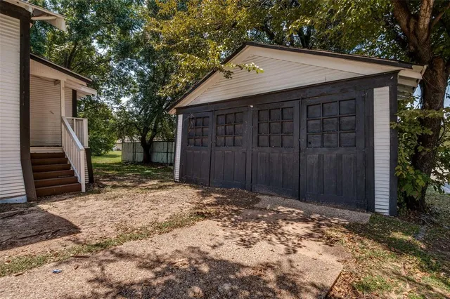 a view of wooden house with a large window and wooden fence