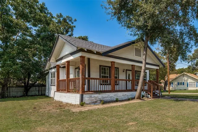 a view of a house with a big yard and large trees