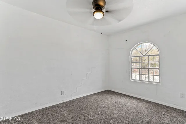 an empty room with a window and a fan
