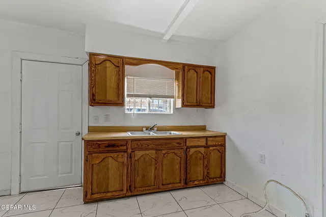 a utility room with stainless steel appliances wooden cabinets and a sink