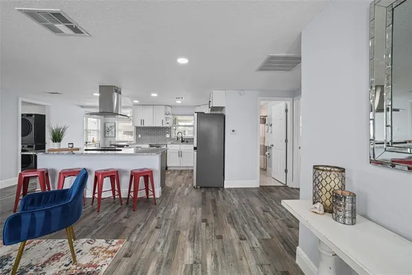a kitchen with stainless steel appliances granite countertop a dining table chairs sink refrigerator and microwave