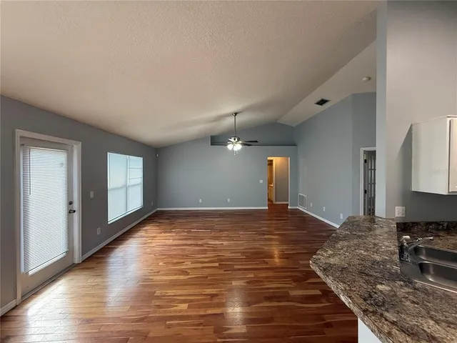 a view of a livingroom with wooden floor and kitchen