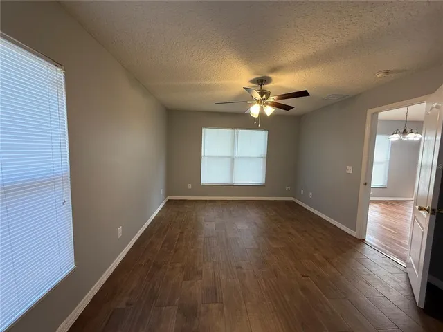 an empty room with wooden floor and ceiling fan