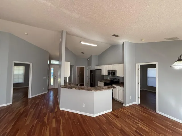 a view of a kitchen with cabinets appliances wooden floor and a window