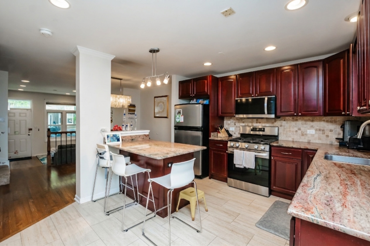 1139 West Roscoe Street Chicago, IL 60657 - Photo 8 of 28 a kitchen with granite countertop a stove top oven a sink dishwasher a dining table and chairs with wooden floor