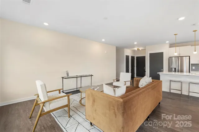 a living room with couches and kitchen view with wooden floor